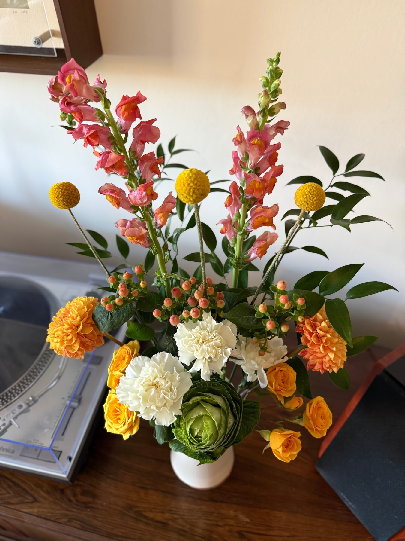 Snapdragons, craspedia and roses in a bold orange and pink palette