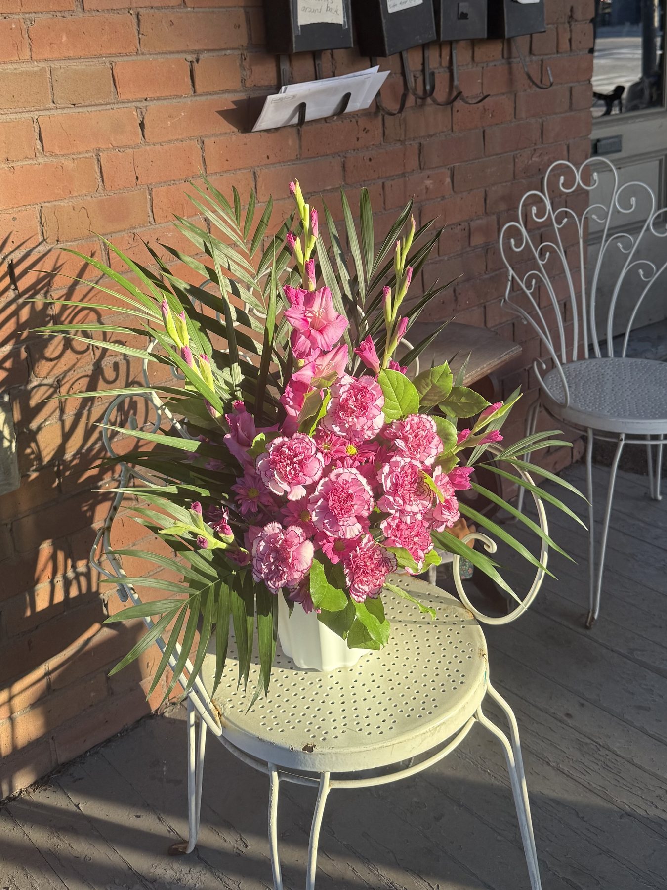 Pink carnation and gladiolus arrangement with palm fronds