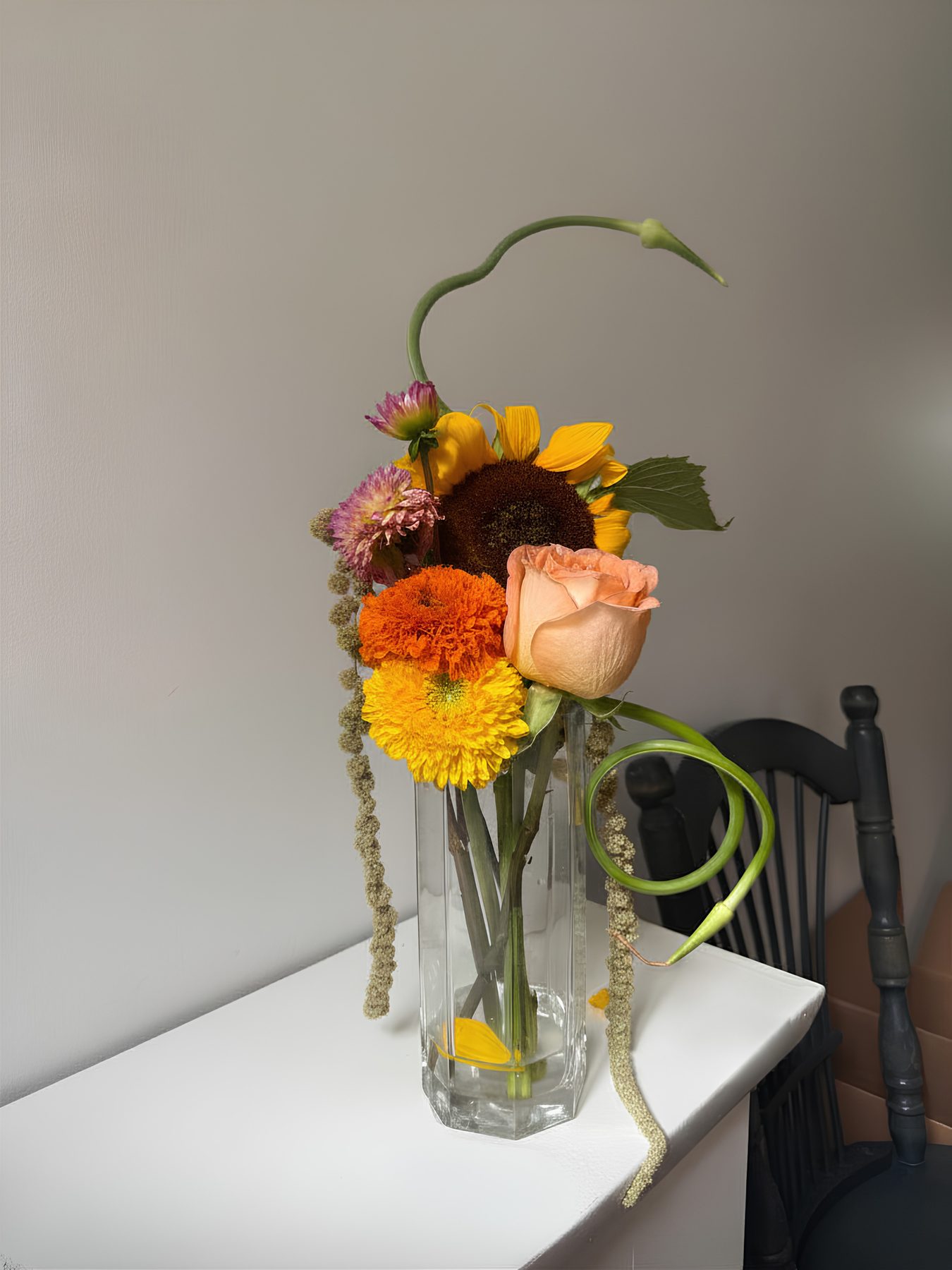 Sunflower and dahlia arrangement in a glass vase on a white mantel