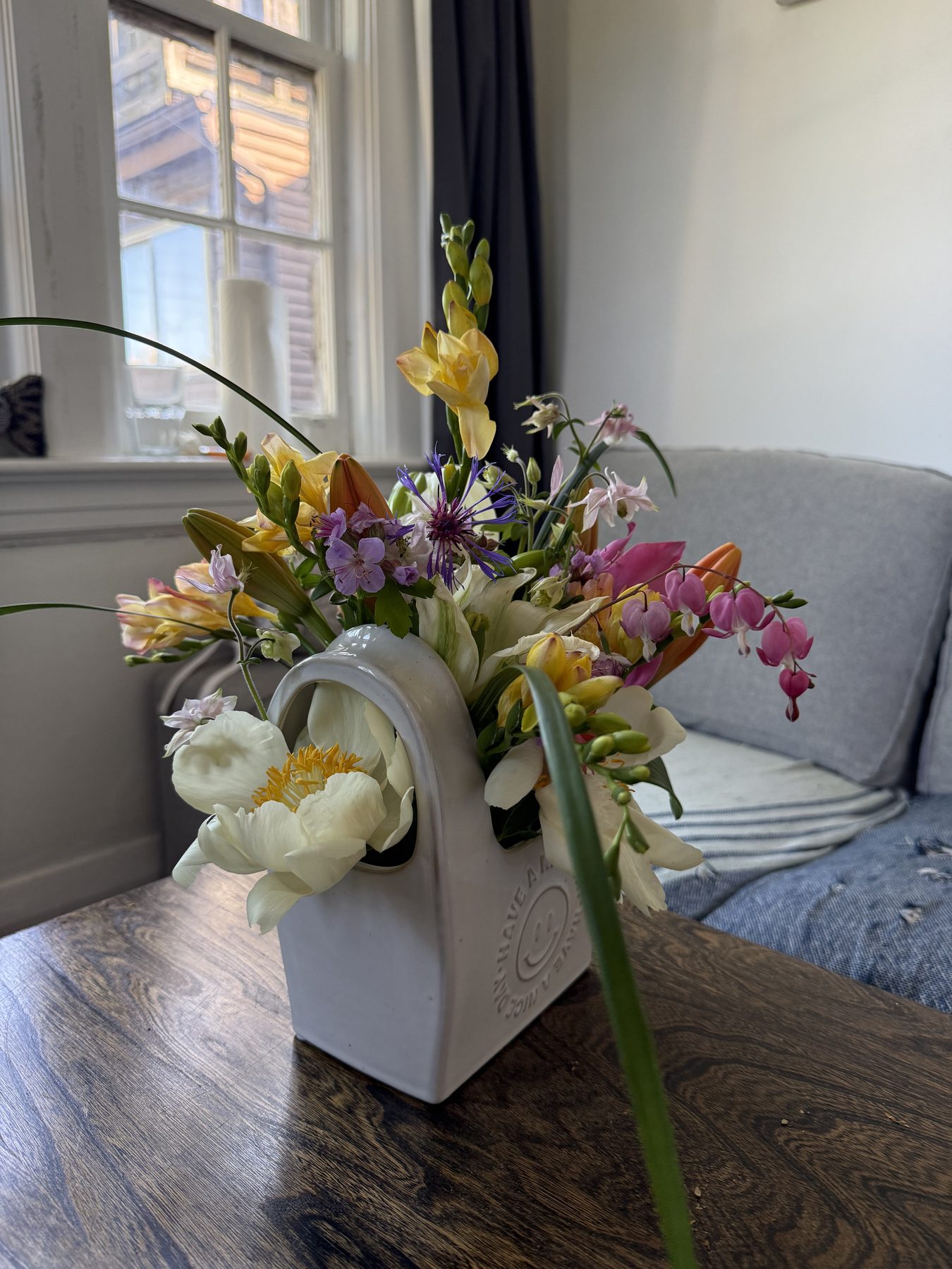 Soft pastel spring bouquet with tulips, freesia and bleeding hearts in a white vase